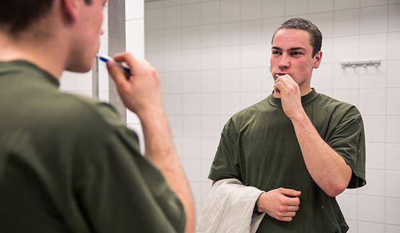 En soldat tvättar sina tänder med en handduk i ena handen