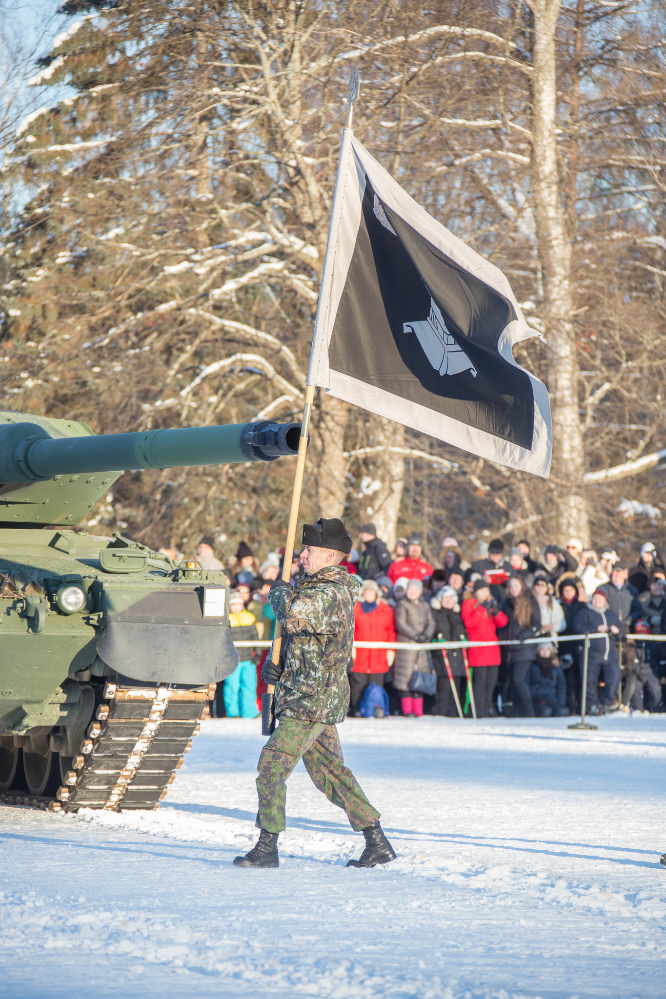 Sotilas kantaa mustavlkoista lippua paraatikentällä