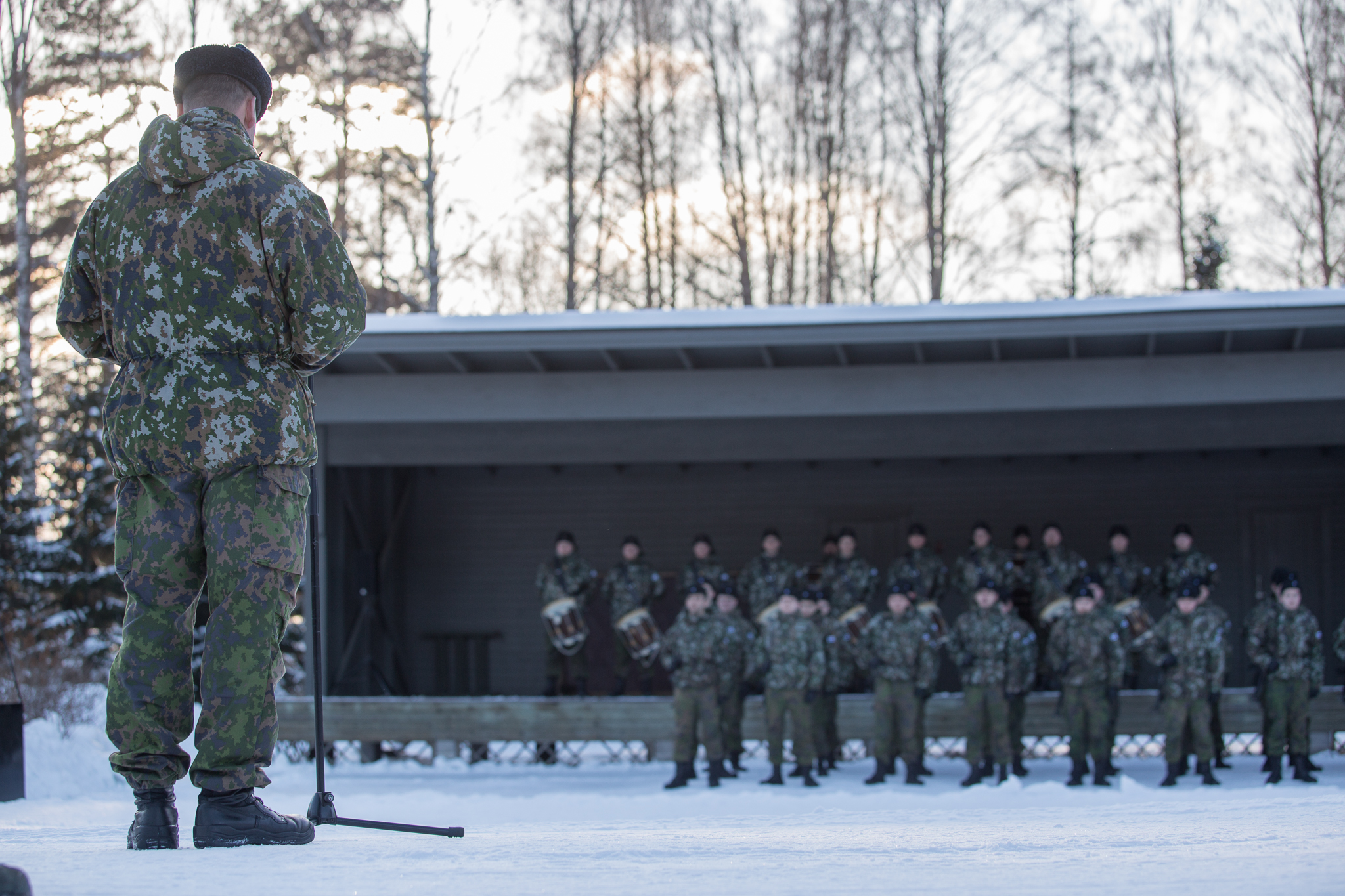 Sotilas puhuu mikrofoniin sotilaille jotka seisovat muodossa