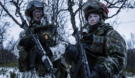 Kaksi sotilasta talvisessa metsässä taisteluvarustuksessa